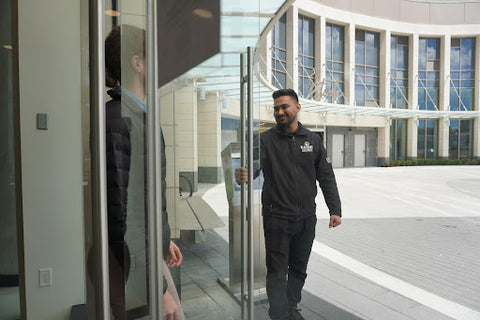 Uniformed Blackbird security guard opening door