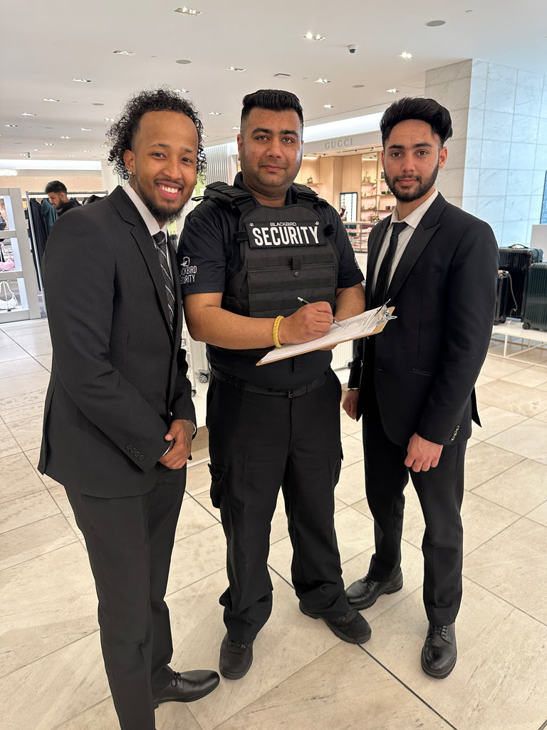 Plained Clothes and Uniformed Blackbird security guard in retail location with clipboard
