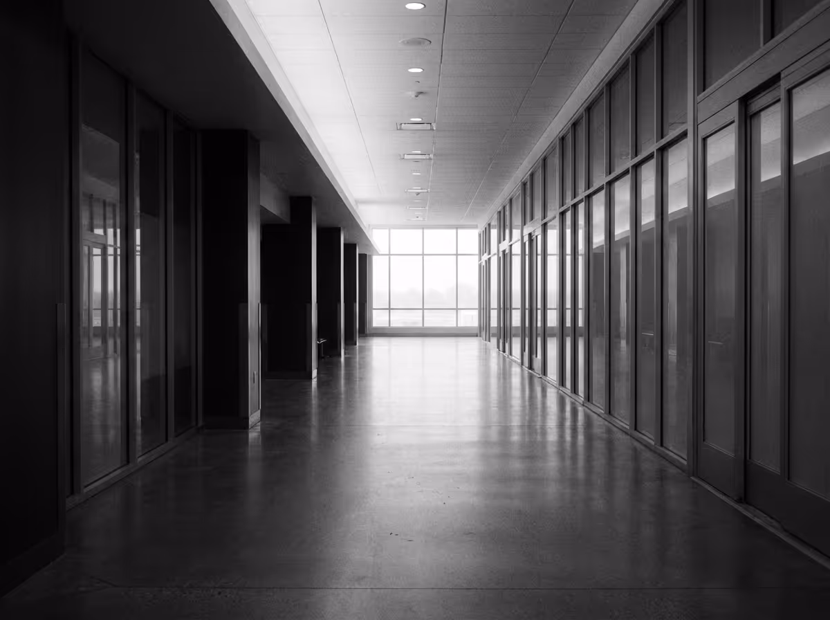 Empty modern hallway with glass doors and large window at the far end, in black and white.