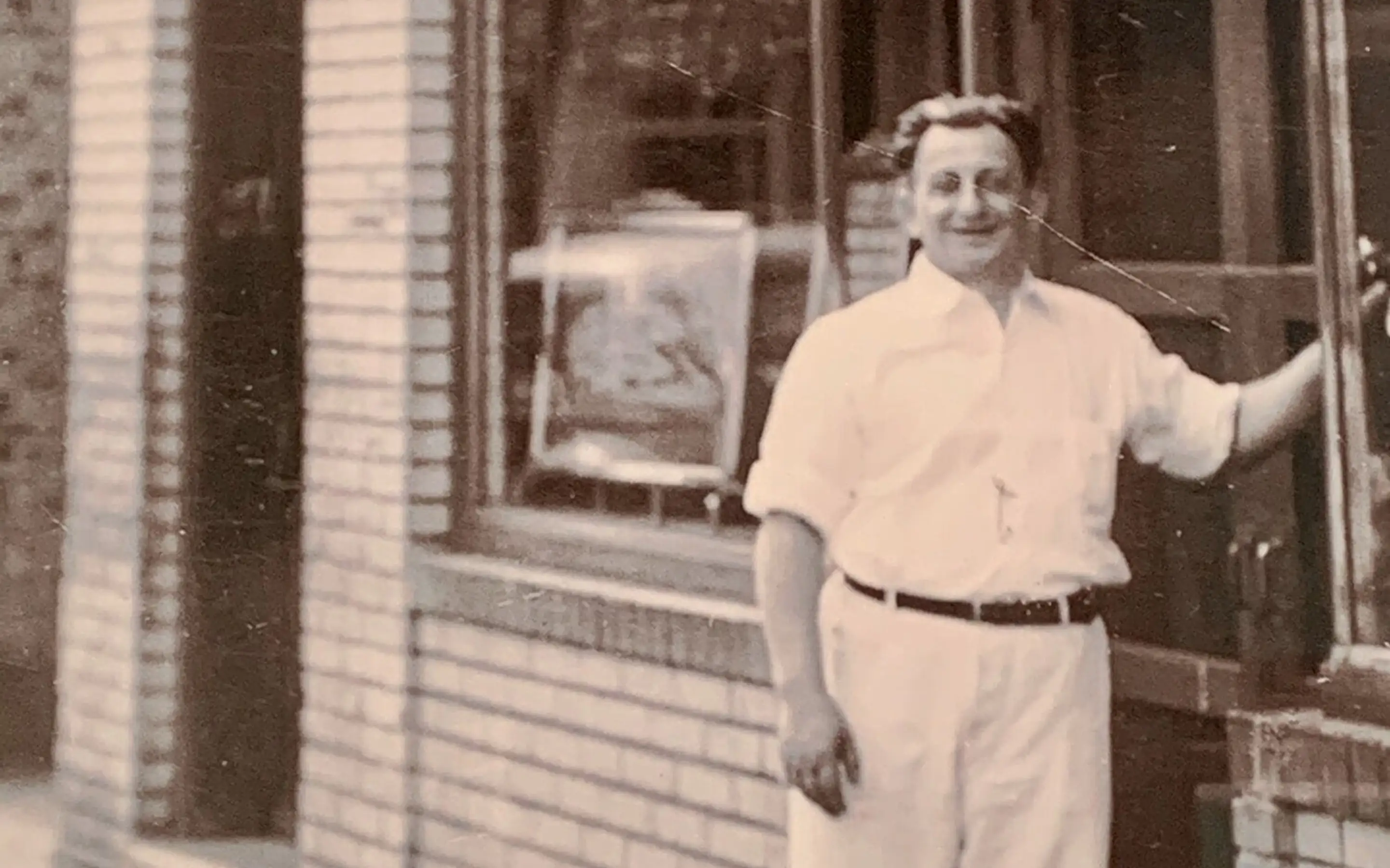 An old photo of a man outside a pizzeria
