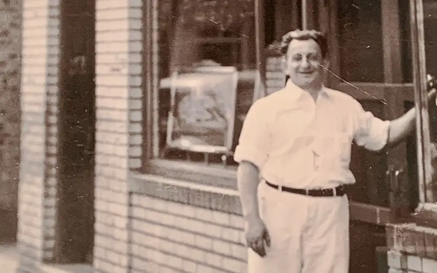 An old photo of a man outside a pizzeria