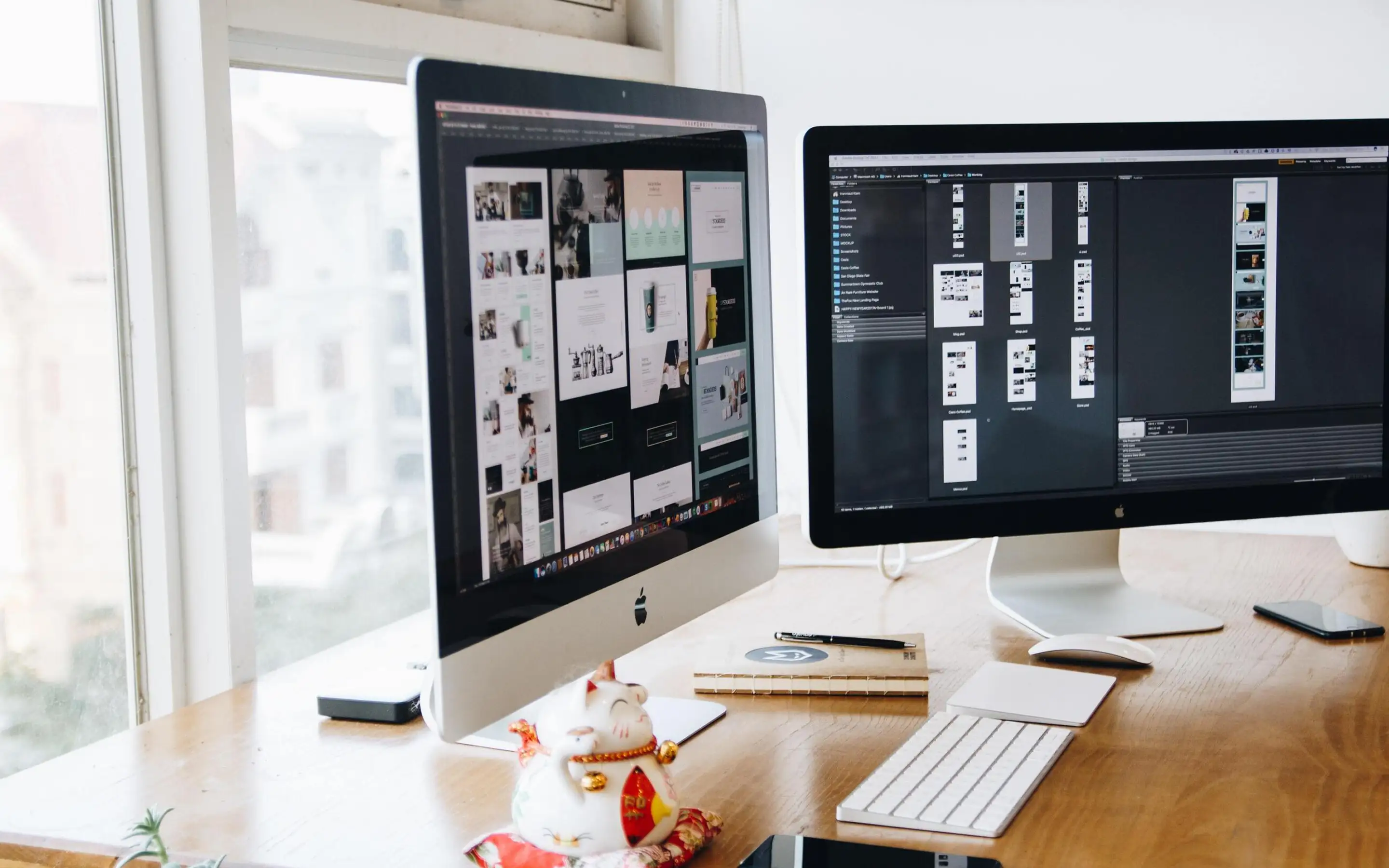 two monitors standing on a table with design tools open