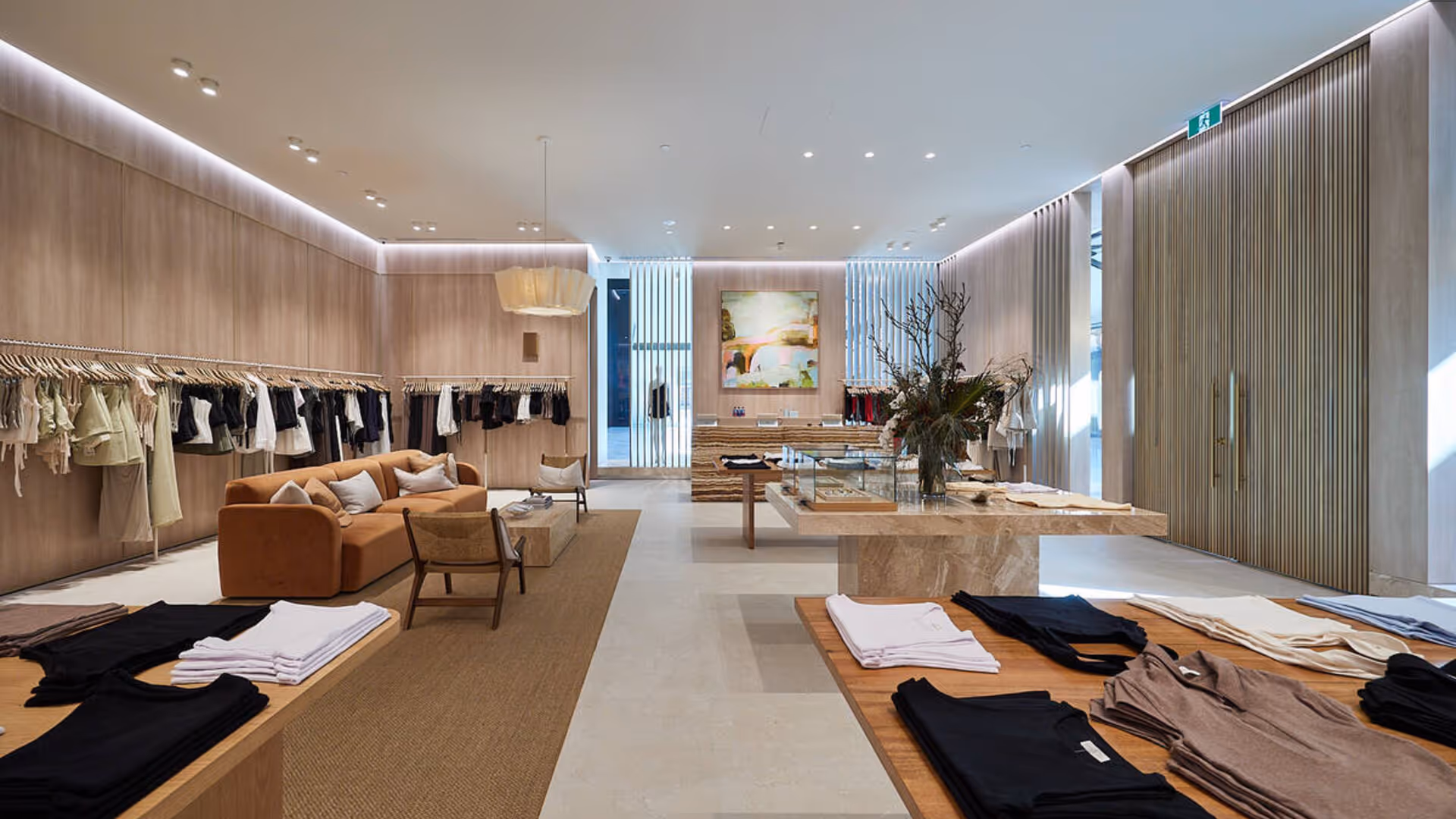 Modern kitchen with dark cabinetry, gray marble island with three black bar stools, and a vase of greenery on the countertop.