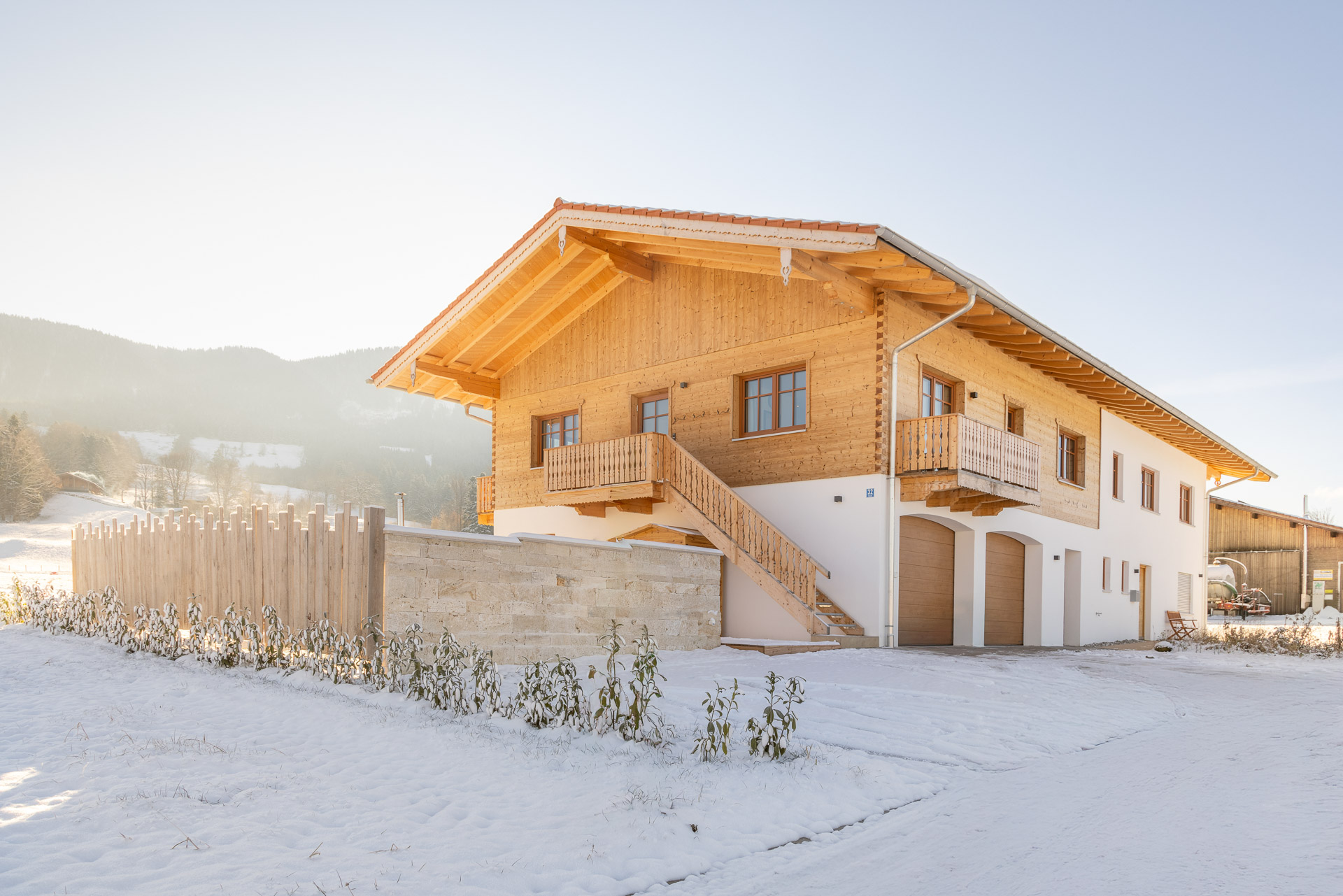 Außenansicht der AlpenLodge Samerberg im Winter mit Parkmöglichkeiten und Bergblick