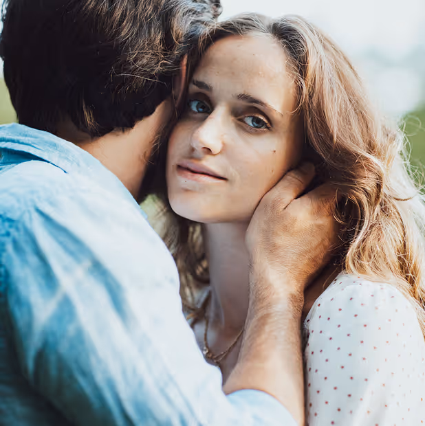 Man gently holding a woman’s face as she looks thoughtfully into the distance.