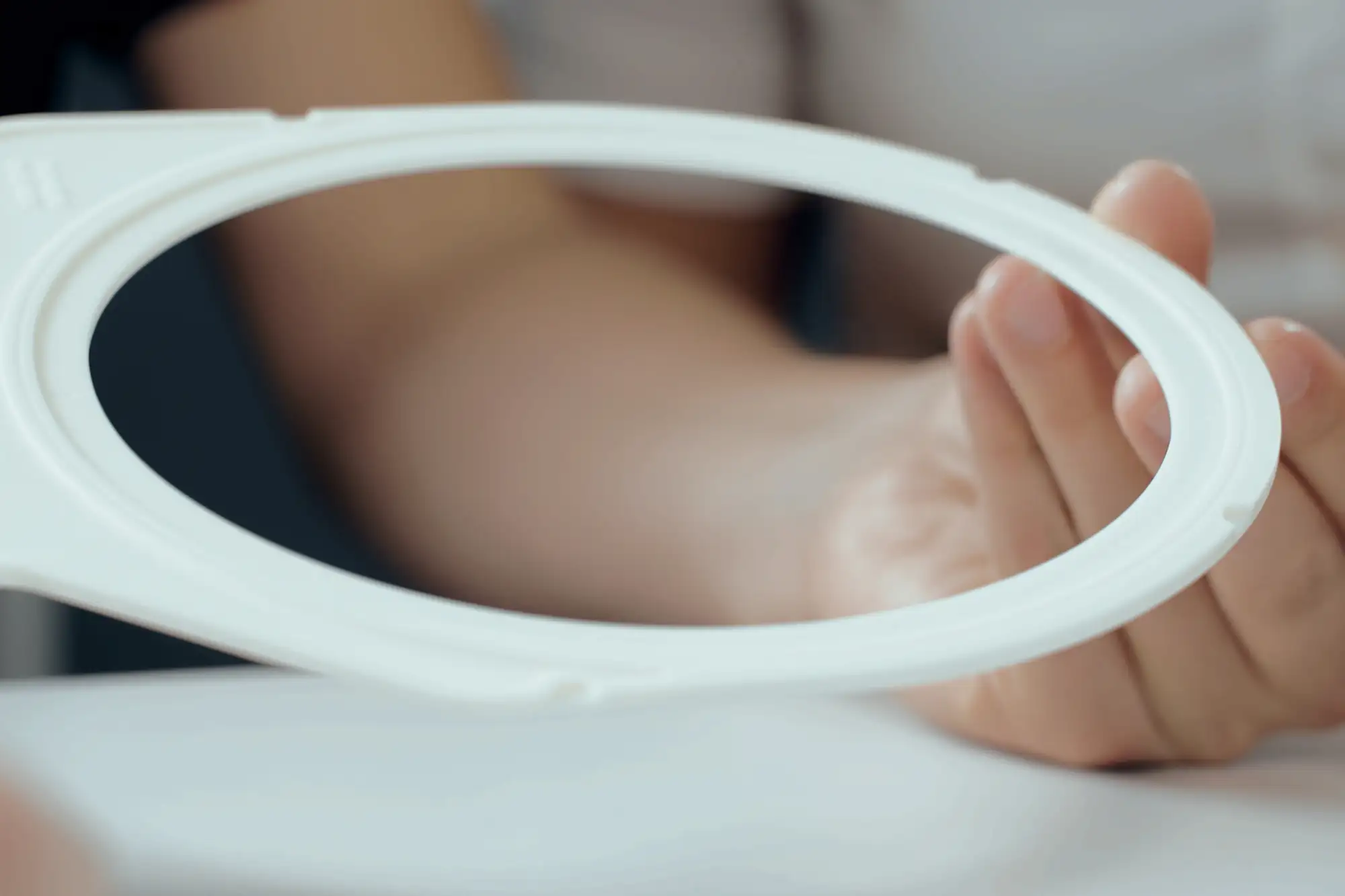 Close-up of hands holding a technical ceramic ring with blurred background.