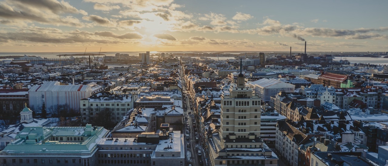 Helsingin kaupunkinäkymä talvella, lumiset katot ja kadut ilta-auringon valaistuksessa.