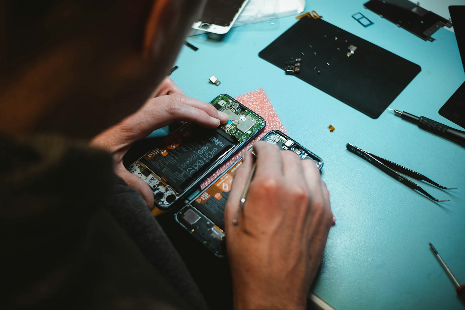 Close-up of a technician repairing a disassembled smartphone on a workbench.