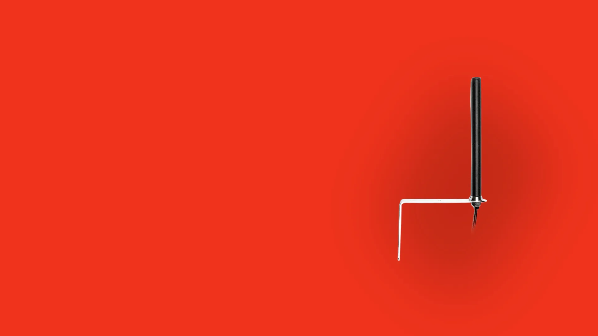 Black external antenna mounted on an L-shaped metal bracket against a red background.
