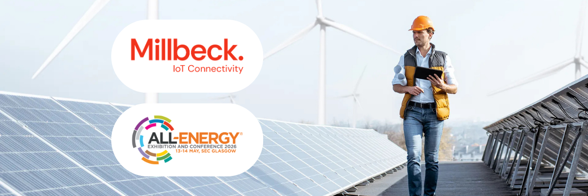 Millbeck and All-Energy logos overlayed on an image of a man in a hard hat walking between solar panels and wind turbines