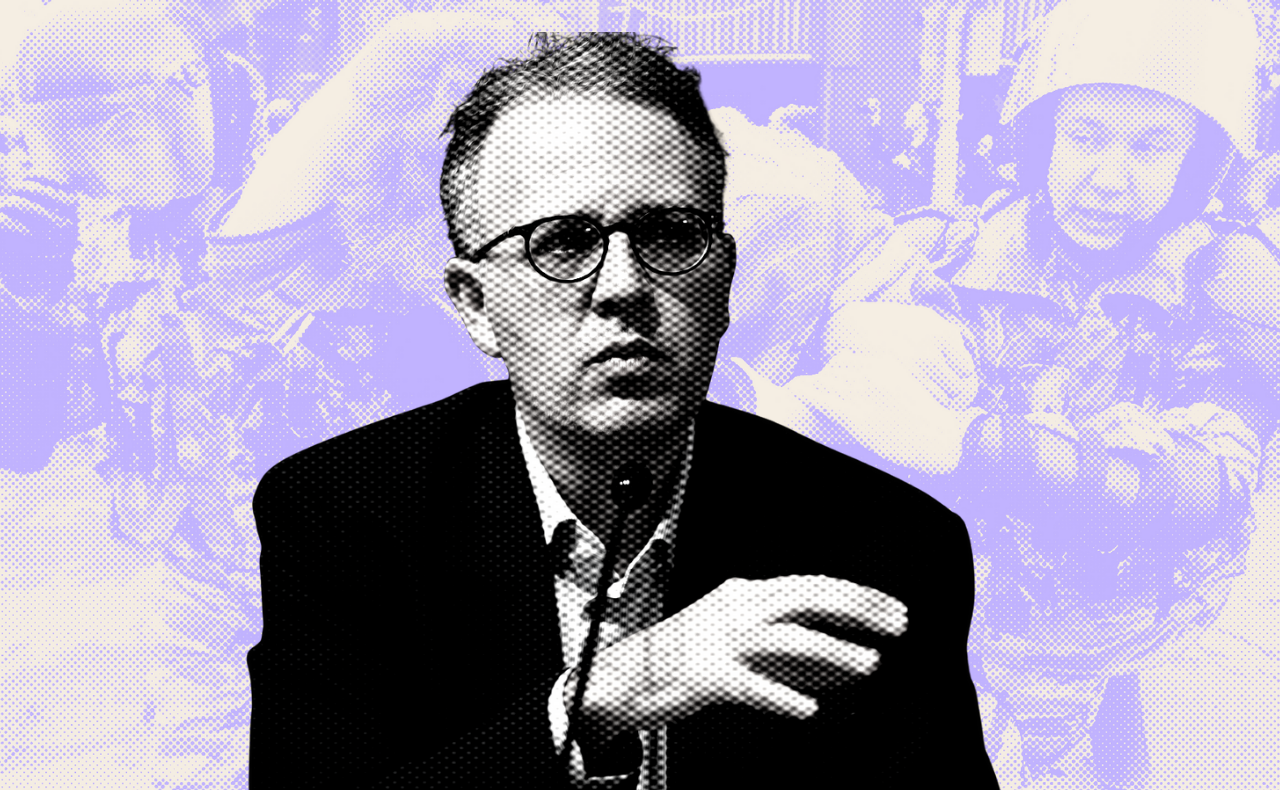 A man holding a camera is being restrained by two riot police officers 