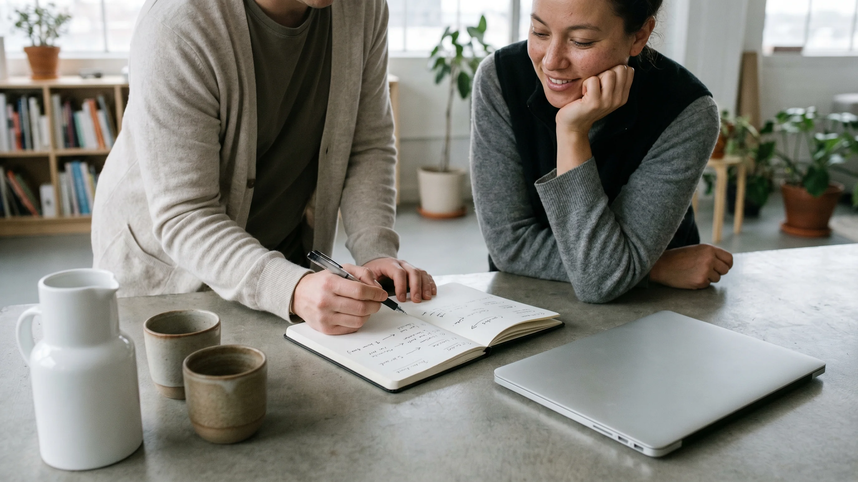 Twee collega's bespreken een workflow-structuur samen aan een werktafel