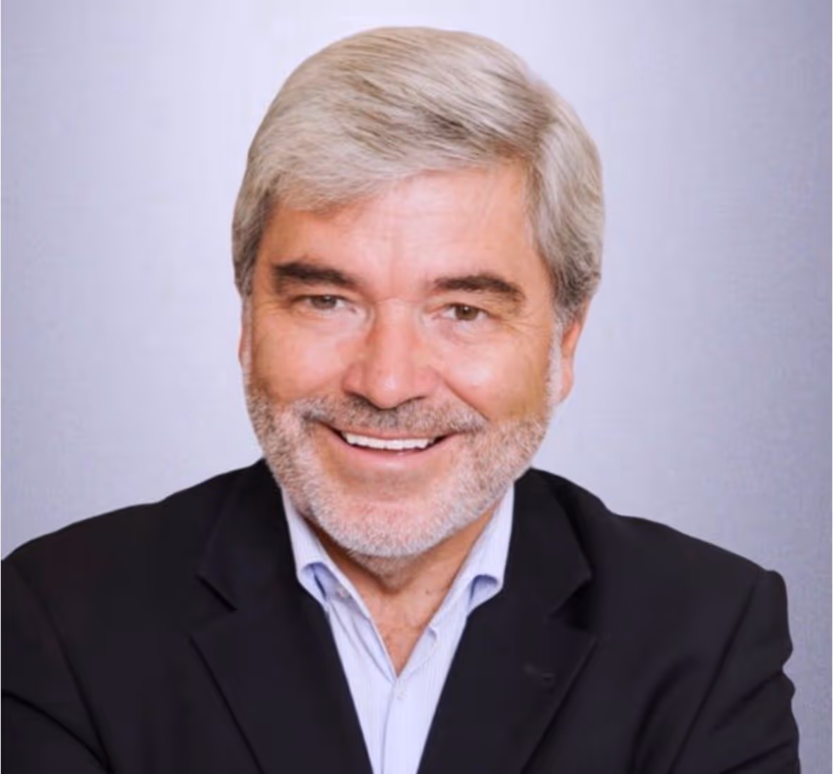 Porträt von Uwe Sieblist, dem Gründer von TOUREC, mit grauem Haar und Bart, der in einem schwarzen Sakko und einem hellen Hemd lächelt.