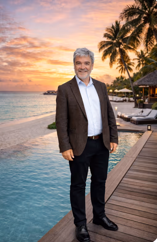 Personalberater Tourismus - Ein älterer Mann lächelnd am Pool mit Palmen und Sonnenuntergang am Strand im Hintergrund.
