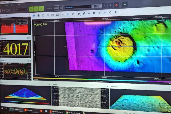 Computer screen displaying a colorful 3D sonar map of a seamount underwater, with data panels showing signal intensity, echo track, and waveform analysis.