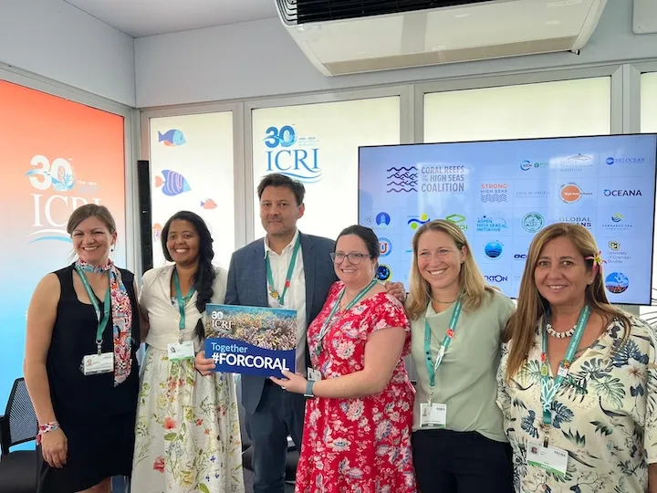 Group of six people smiling indoors, holding a sign that reads 'Together #FORCORAL' with ICRI 30th anniversary logos in the background.