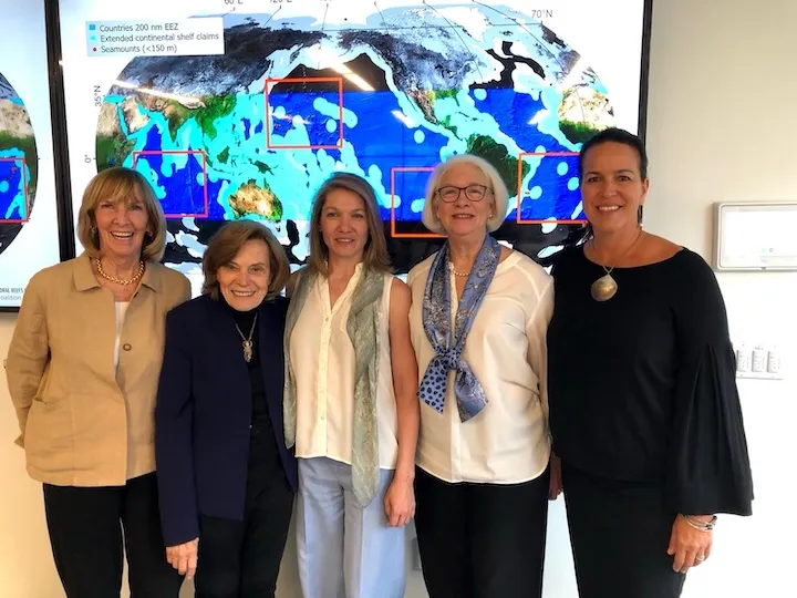 Five women standing indoors in front of a large map showing countries' exclusive economic zones and seamounts.