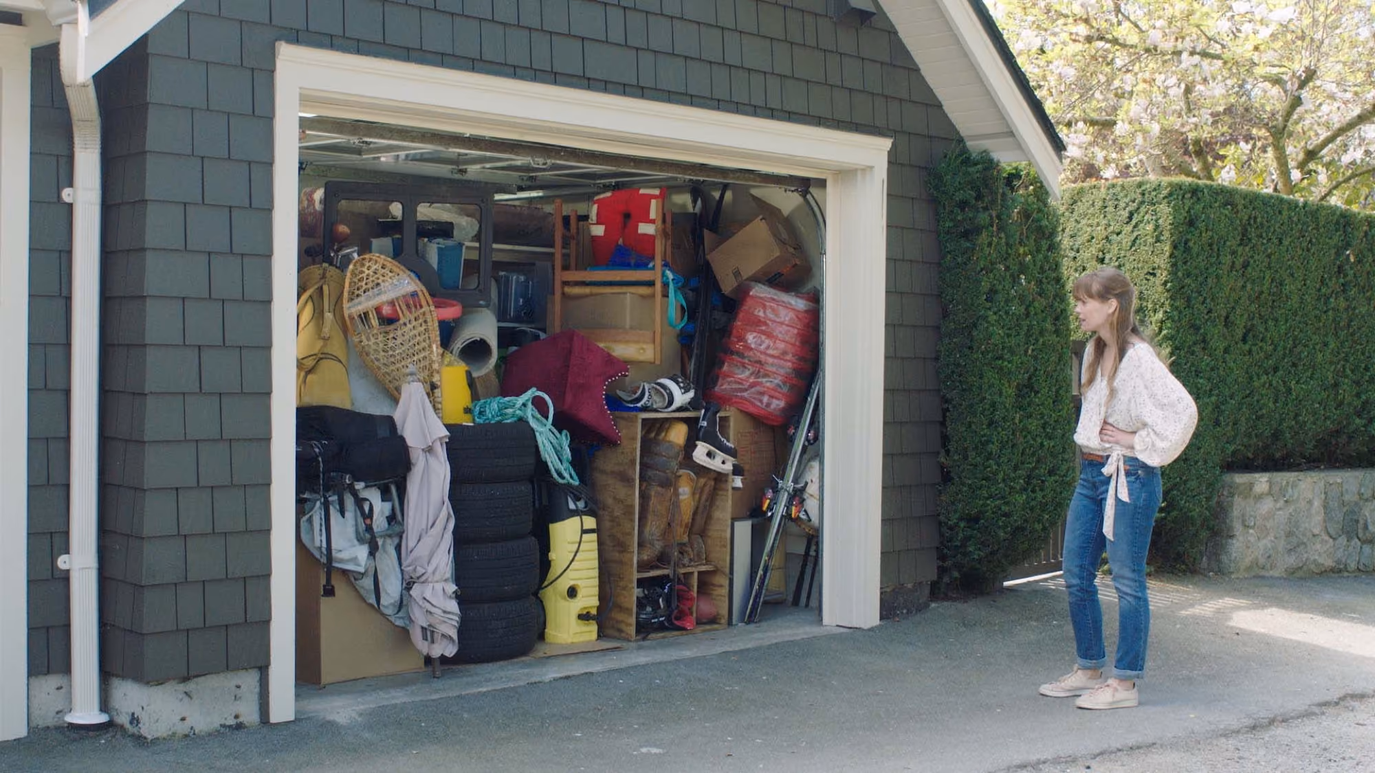 Woman standing in front of an open garage overflowing with stored belongings