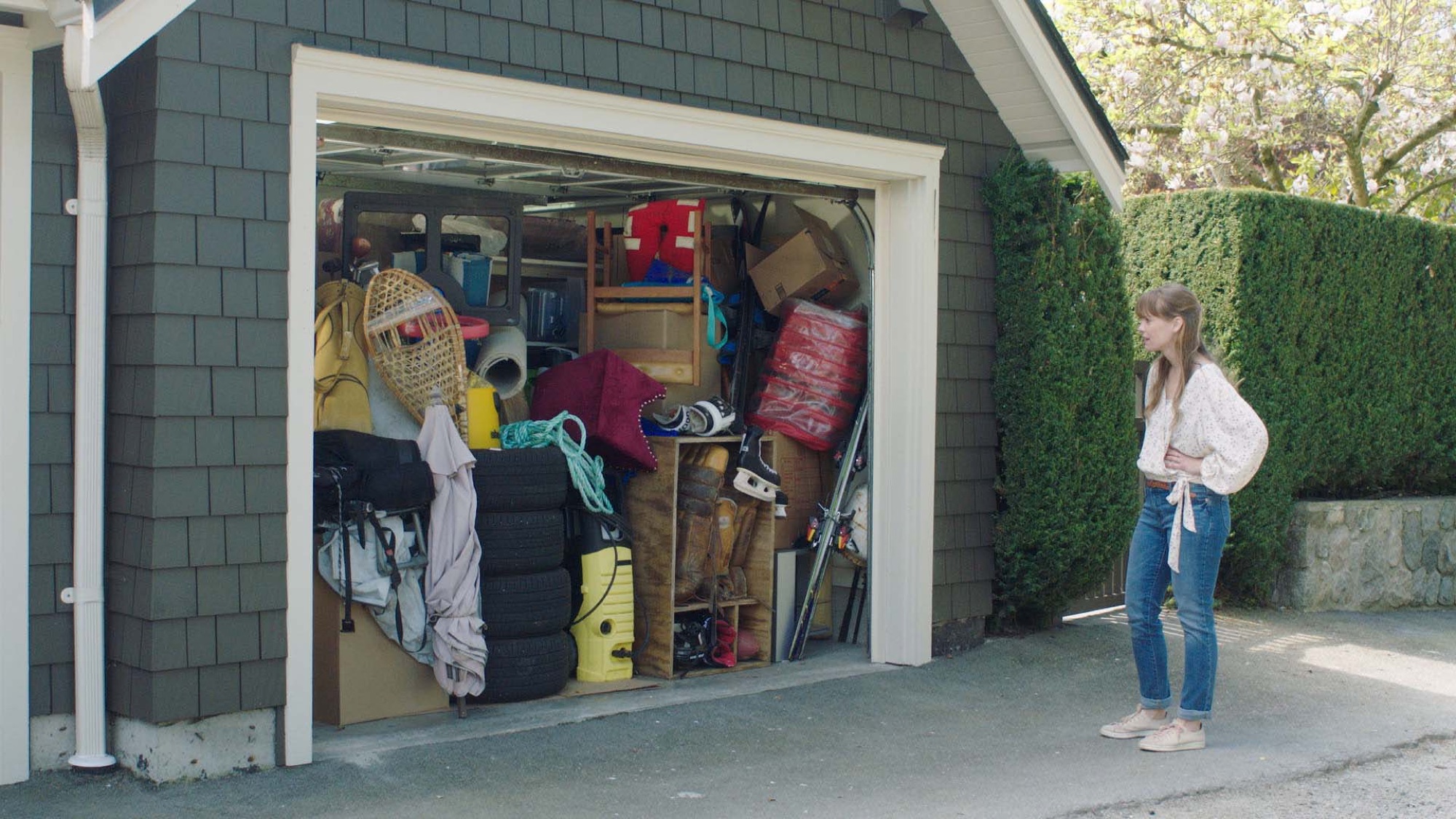 Woman standing in front of an open garage overflowing with stored belongings