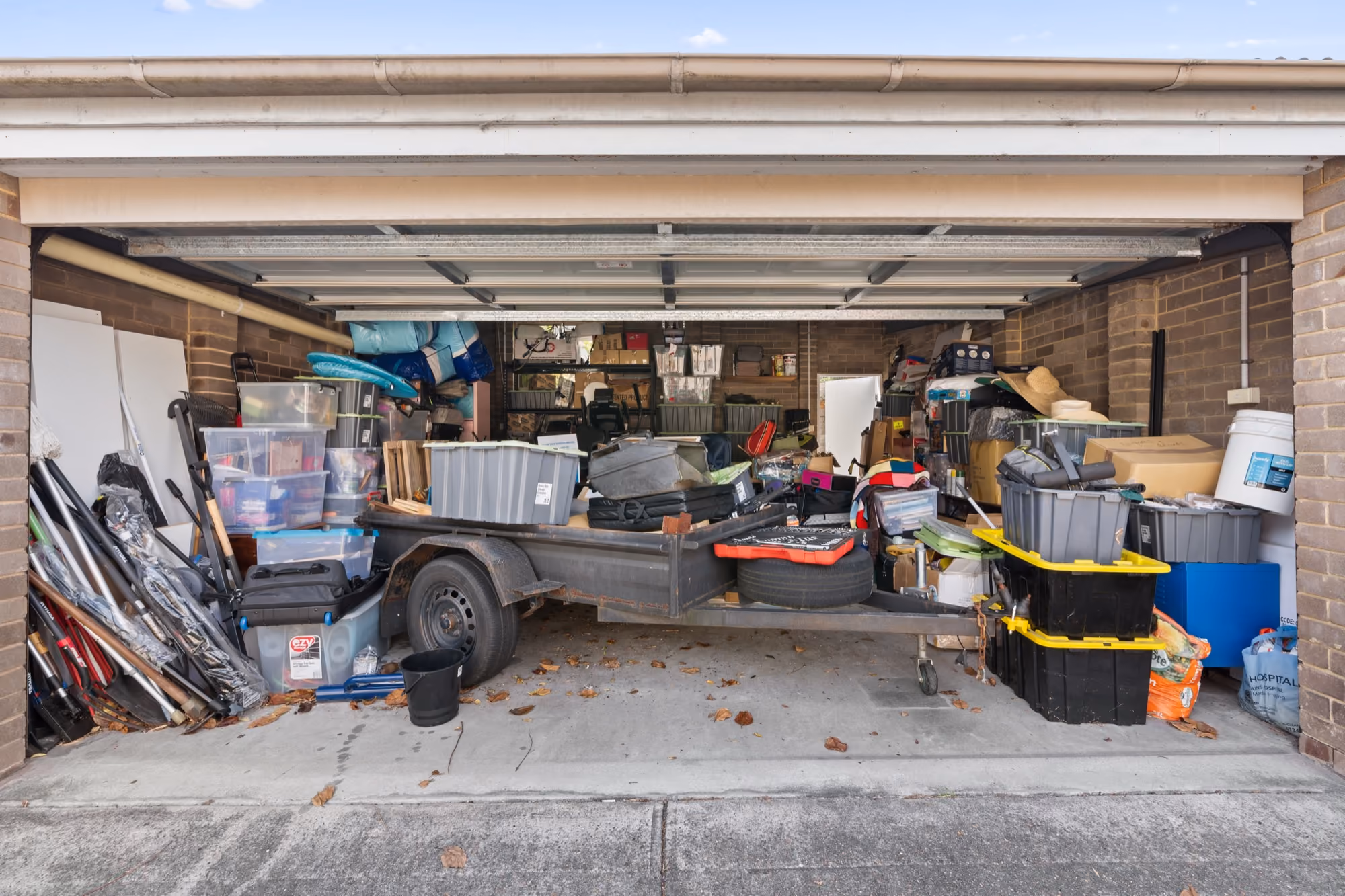 Garage packed floor to ceiling with boxes, bins, and household belongings