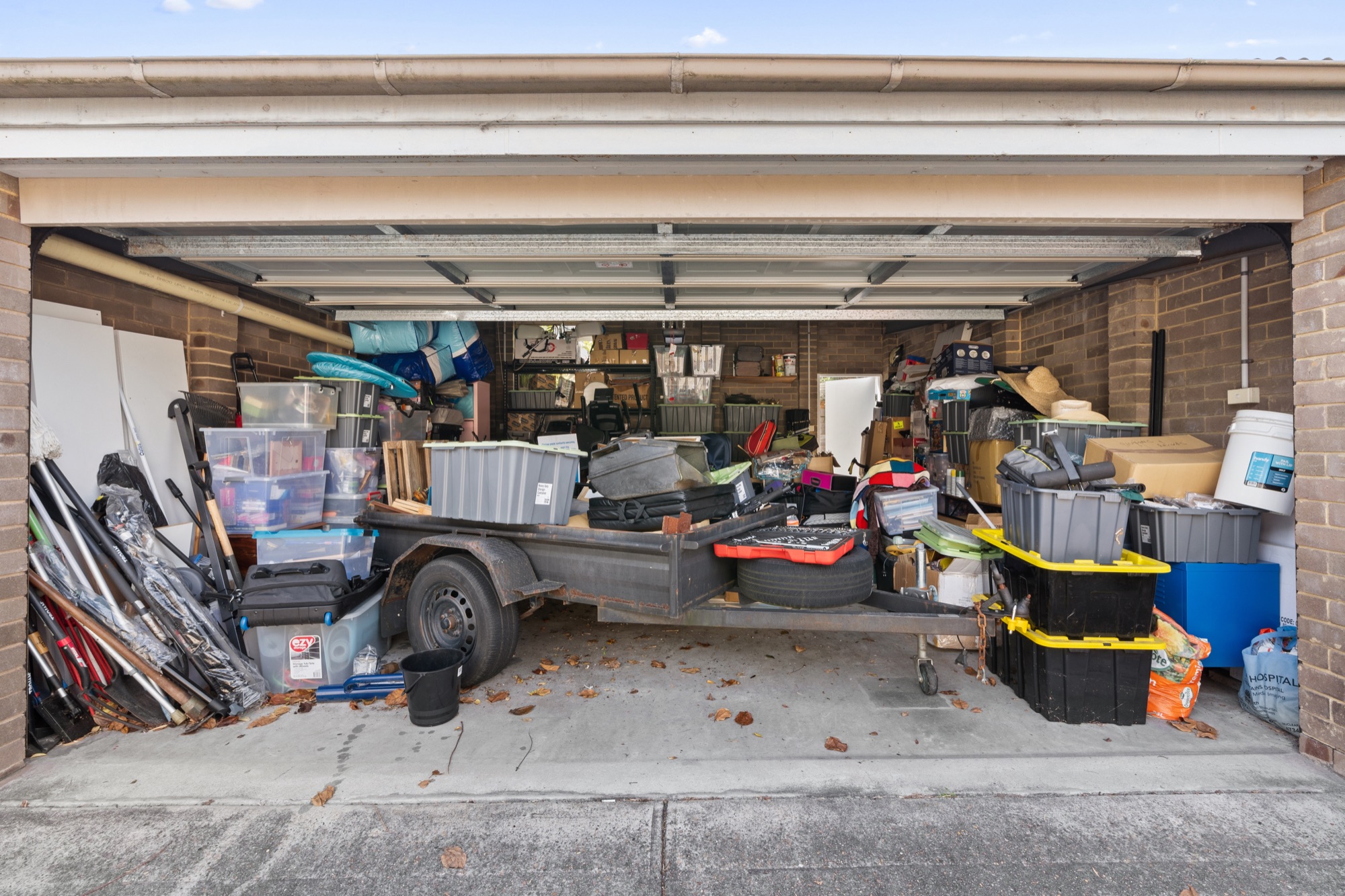 Garage packed floor to ceiling with boxes, bins, and household belongings