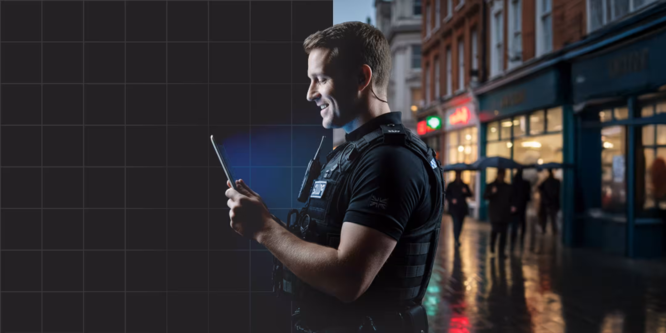 Smiling police officer in uniform and body armor holding a tablet on a rainy city street at night.