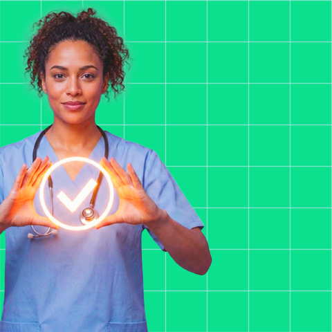 Smiling nurse wearing blue scrubs and a stethoscope holding an illuminated checkmark symbol with both hands in front of a green grid background.