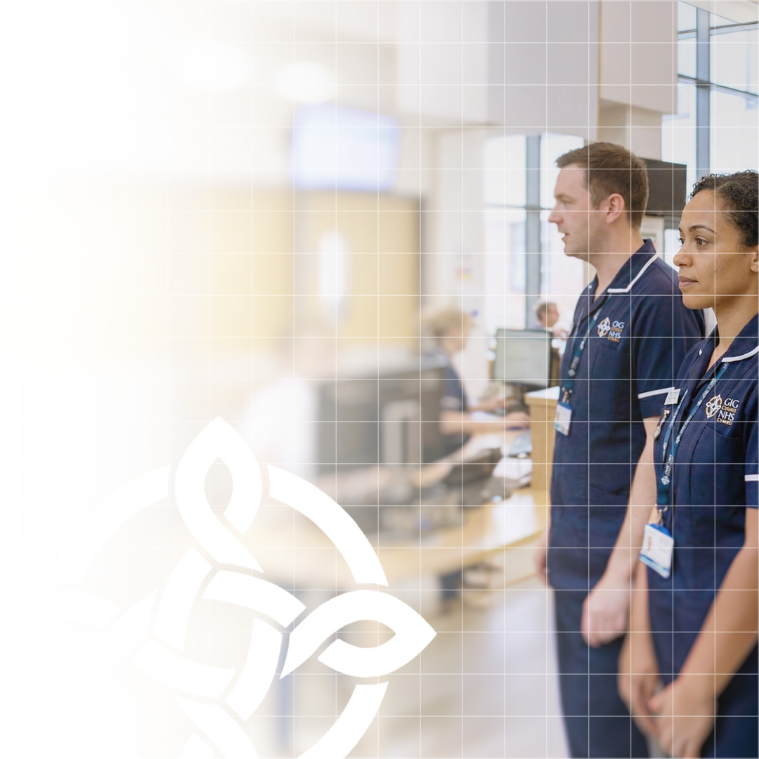 Two healthcare professionals in navy blue uniforms standing in a medical facility reception area.