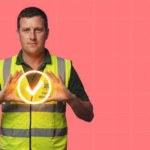 Man in a high-visibility safety vest holding a glowing check mark symbol with a pink grid background.