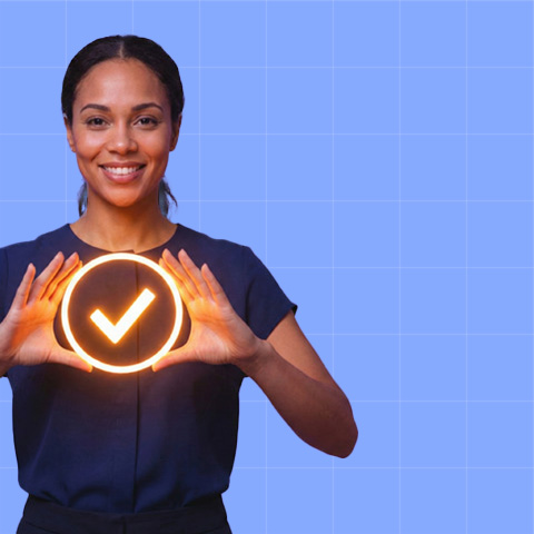 Smiling woman holding a glowing checkmark symbol between her hands against a blue grid background.