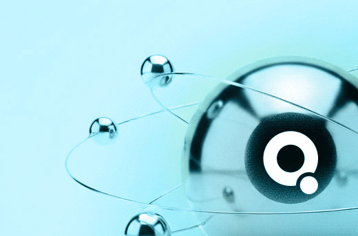 Metallic spheres connected by thin rods, forming an atom-like structure with a stylized letter Q on the largest sphere.