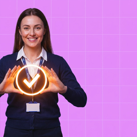 Smiling woman holding a glowing checkmark in front of her against a purple grid background.