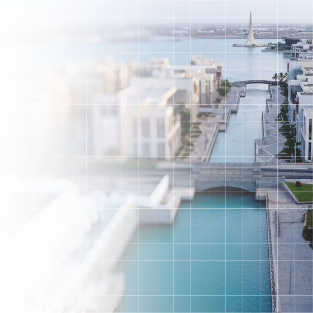 Aerial view of a modern waterfront residential area with canals, bridges, and a tall tower in the distance.