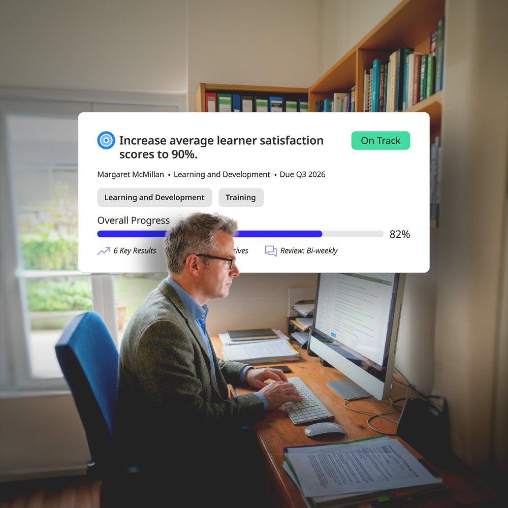 Man in glasses and blazer working at a desk with a computer, with an overlay showing 82% progress on increasing learner satisfaction scores to 90%.