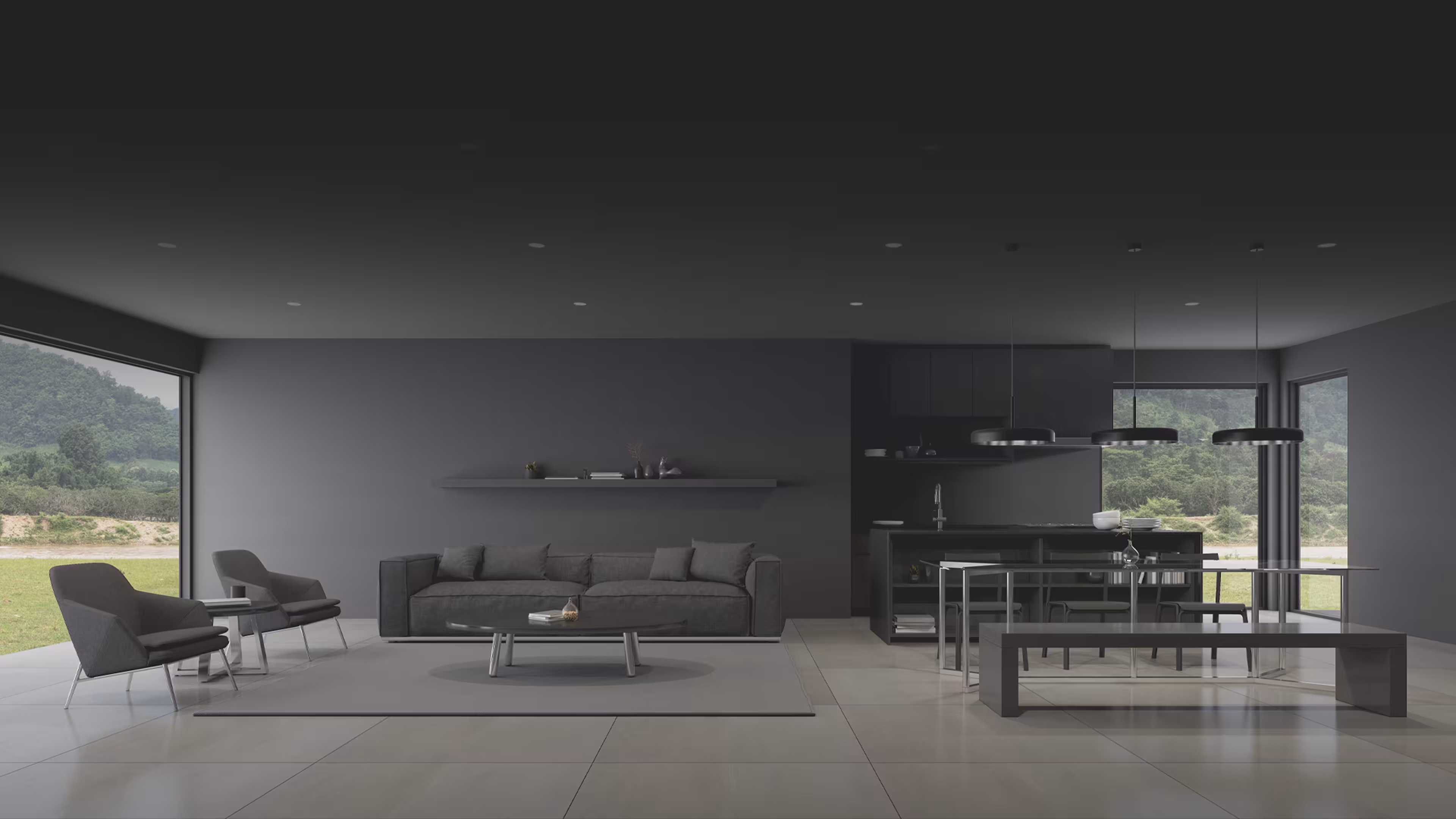 Modern open living room and kitchen with dark gray furniture and large windows showing a green landscape.