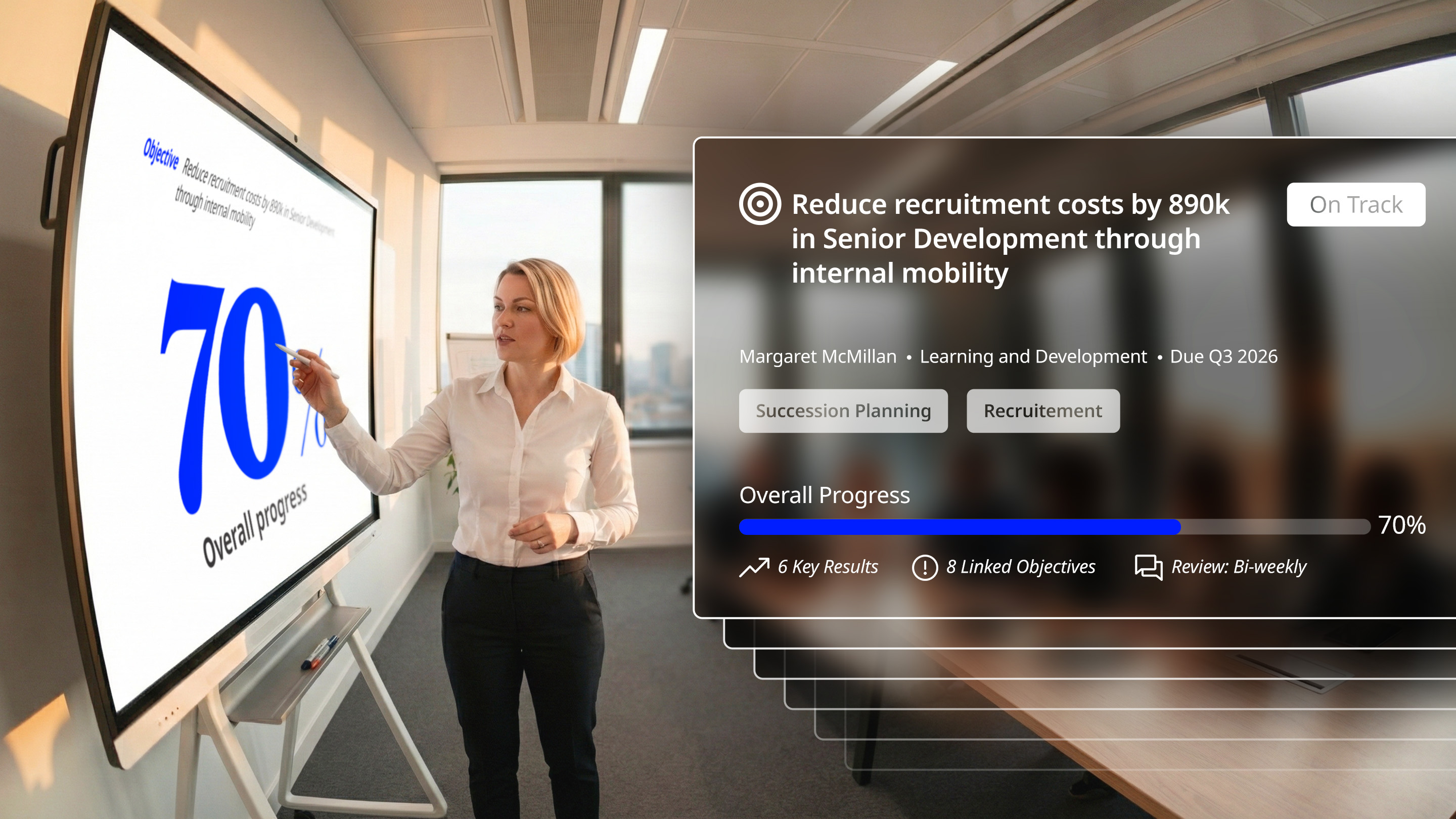 Businesswoman pointing at screen showing 70% overall progress on reducing recruitment costs by 890k through internal mobility in senior development.