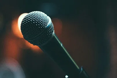 Close-up of a microphone against a dark blurred background with warm light.