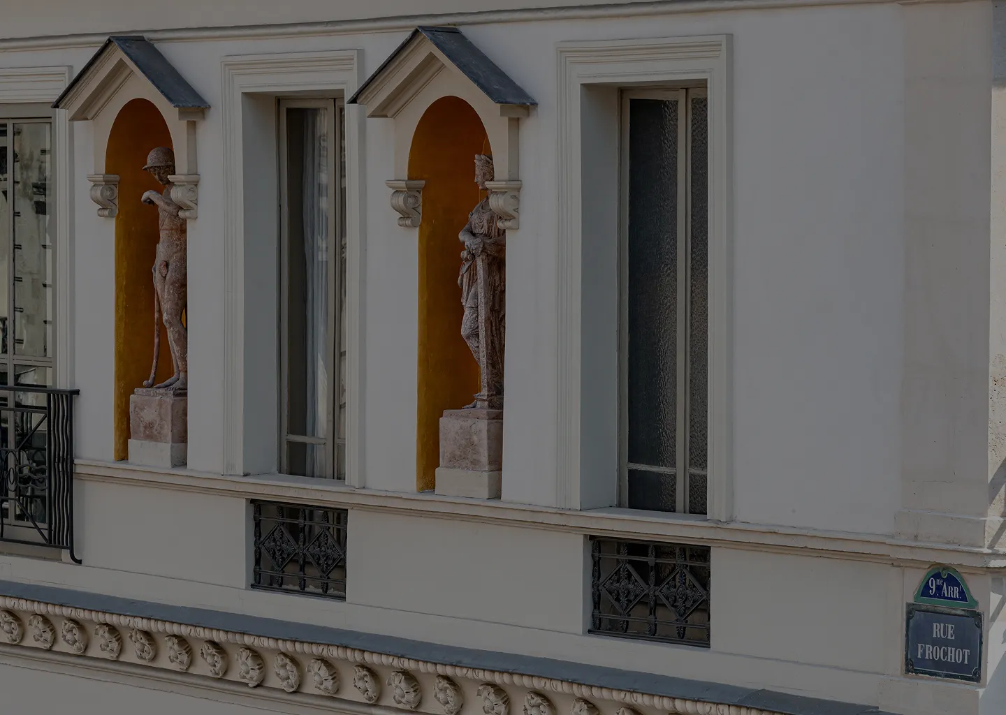 Building facade with two statues in arched niches and a street sign reading 'Rue Frochot' in Paris 9th arrondissement.
