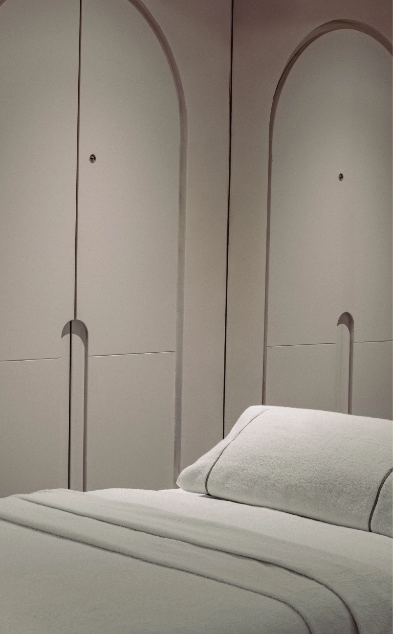 Minimalist room with a white bed neatly made and built-in lockers with arched designs on the doors.