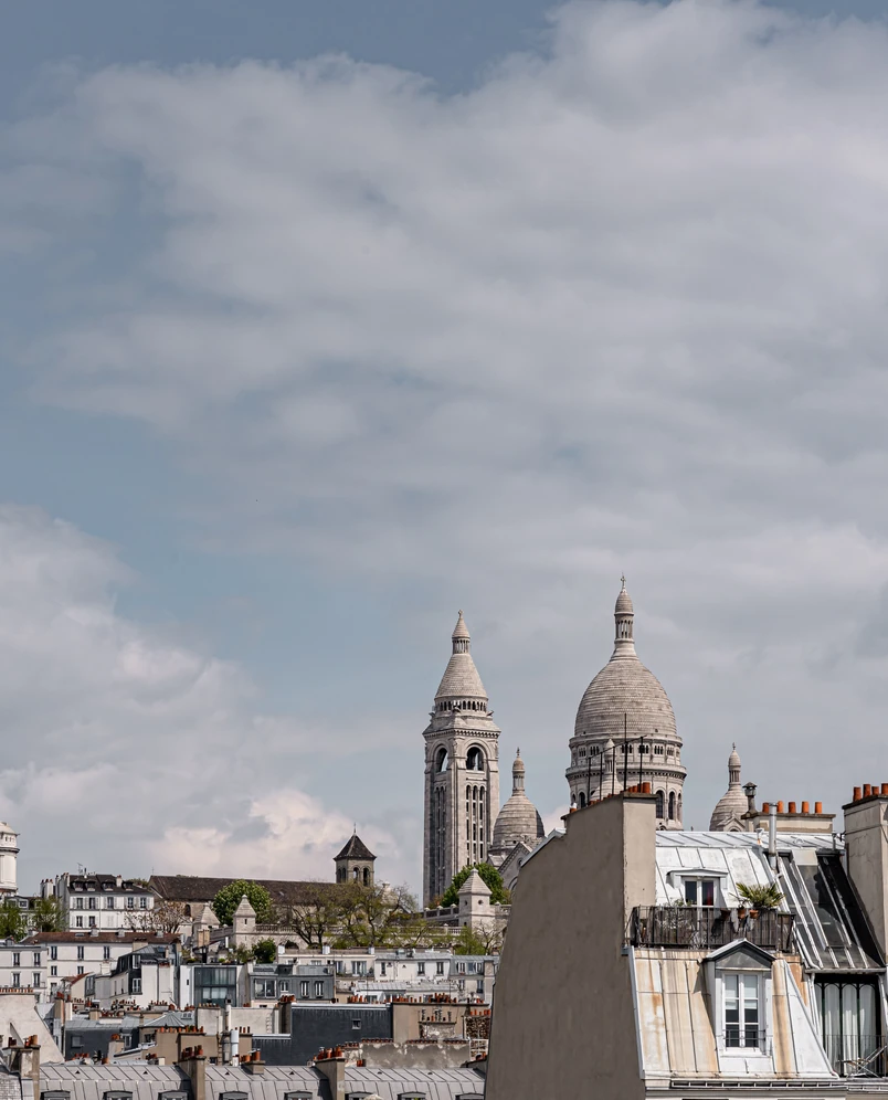 Vista de la basílica del Sagrado Corazón y los tejados de París bajo un cielo nublado.