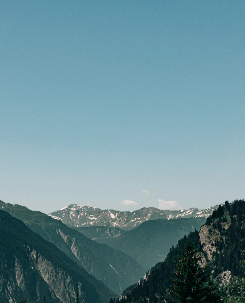 Mountain range with some snow patches under a clear blue sky.
