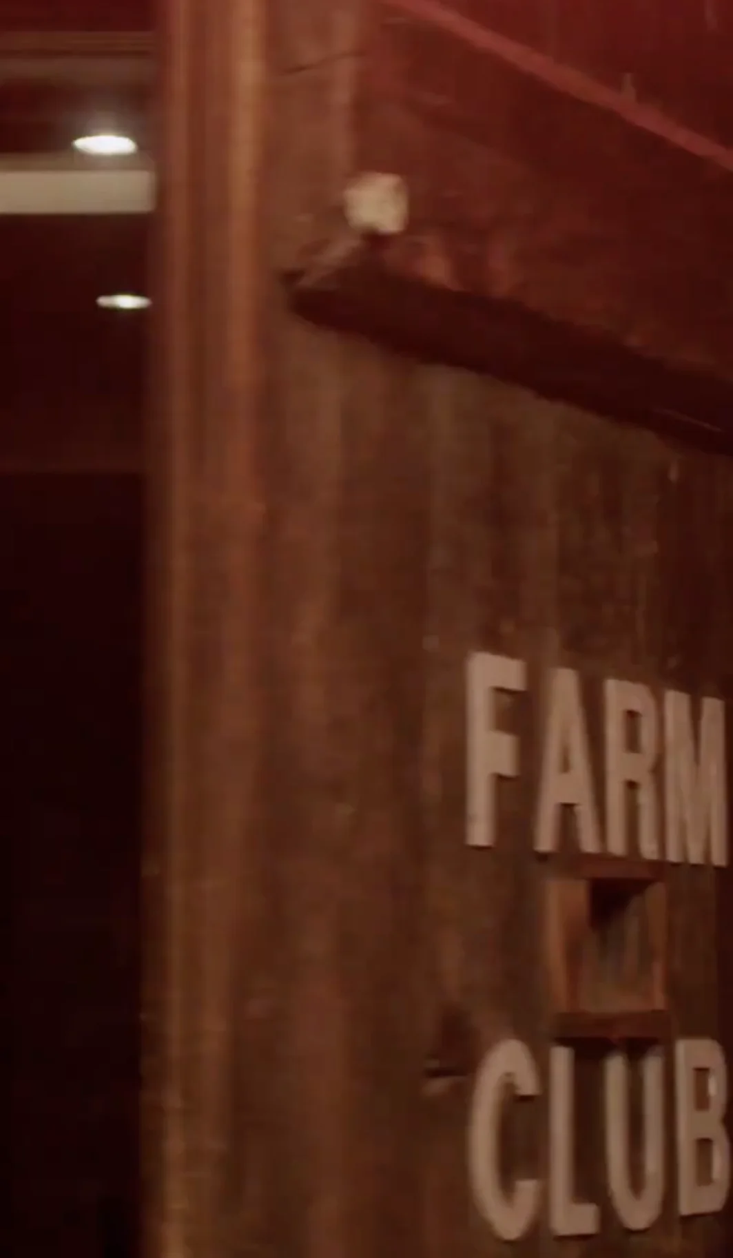 Dimly lit wooden wall with partially visible sign reading 'Farm Club.'