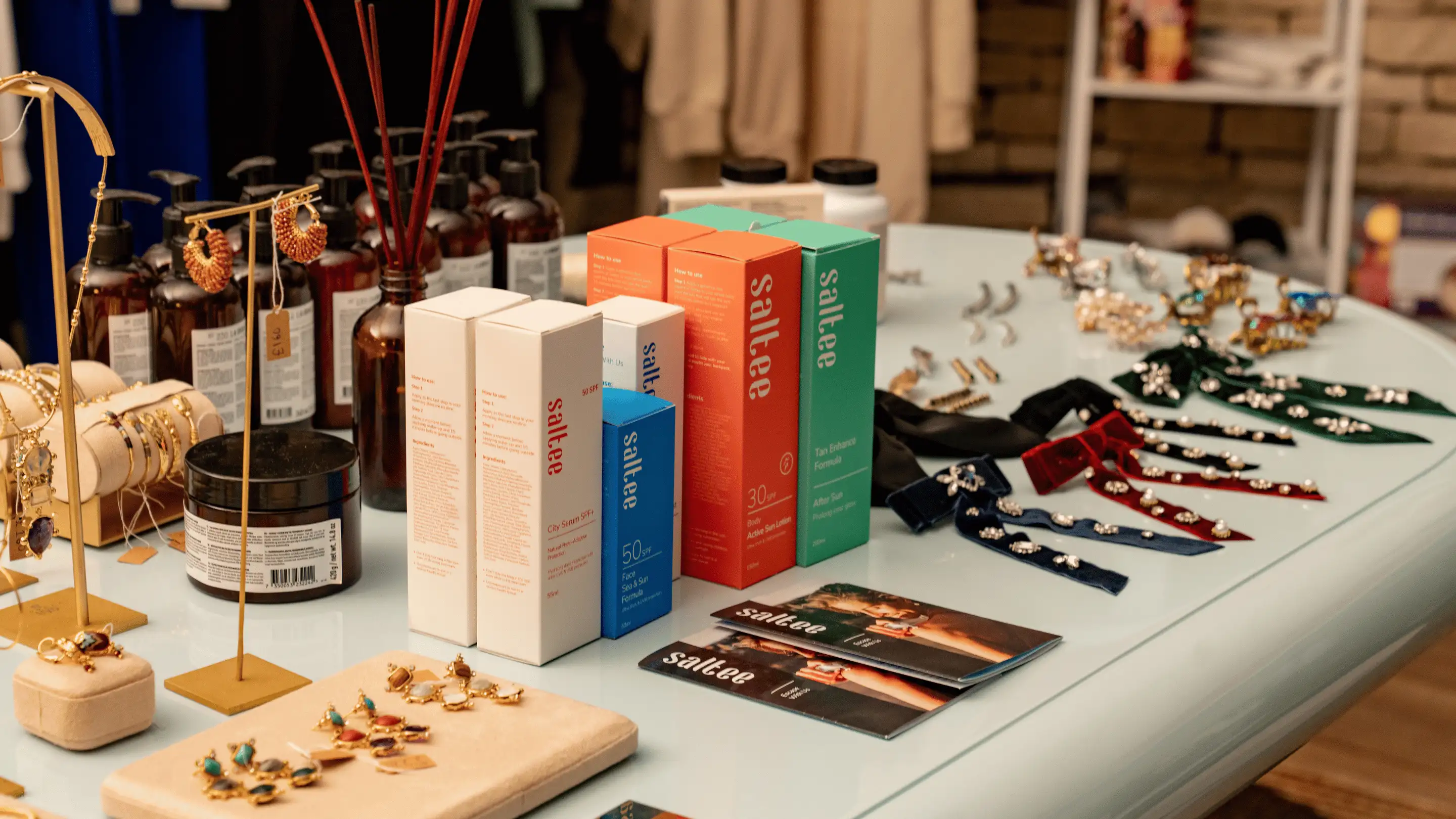 Table display of skincare products, jewelry, and decorative hair clips in a store setting.