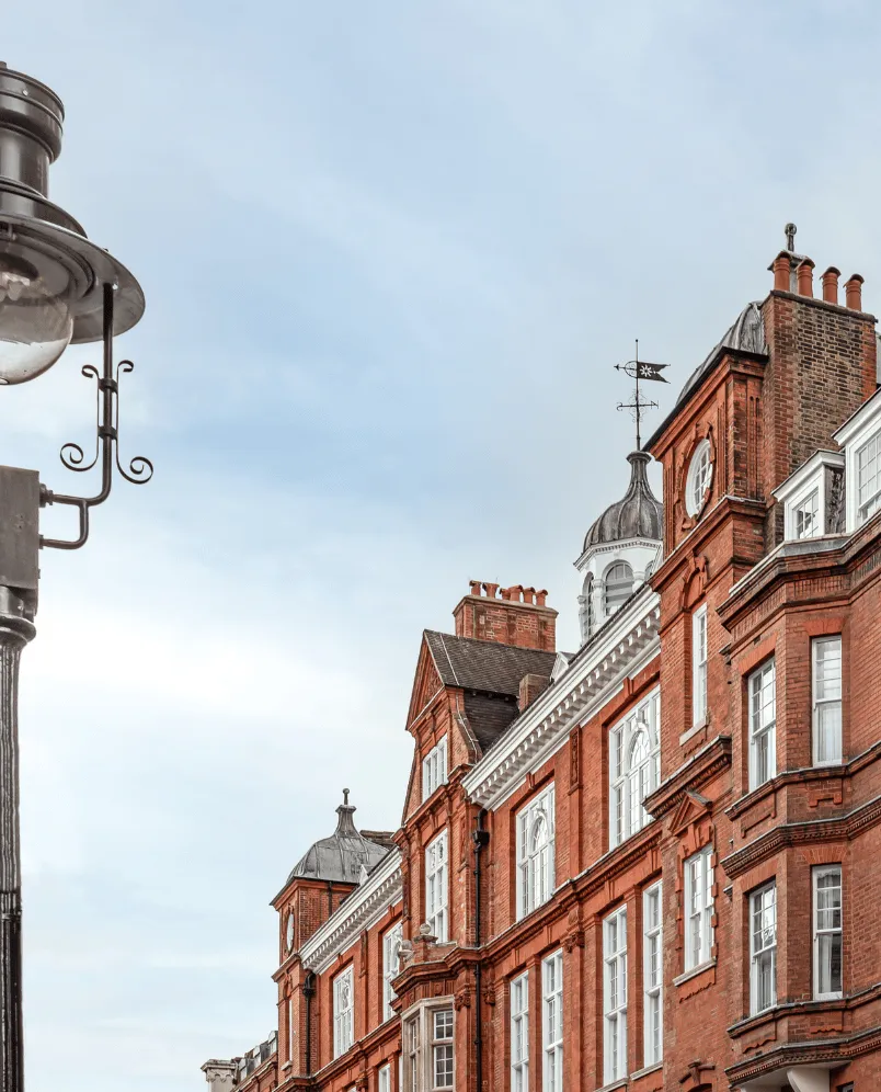 Red brick historic building with white-framed windows and a clock tower under a clear sky.