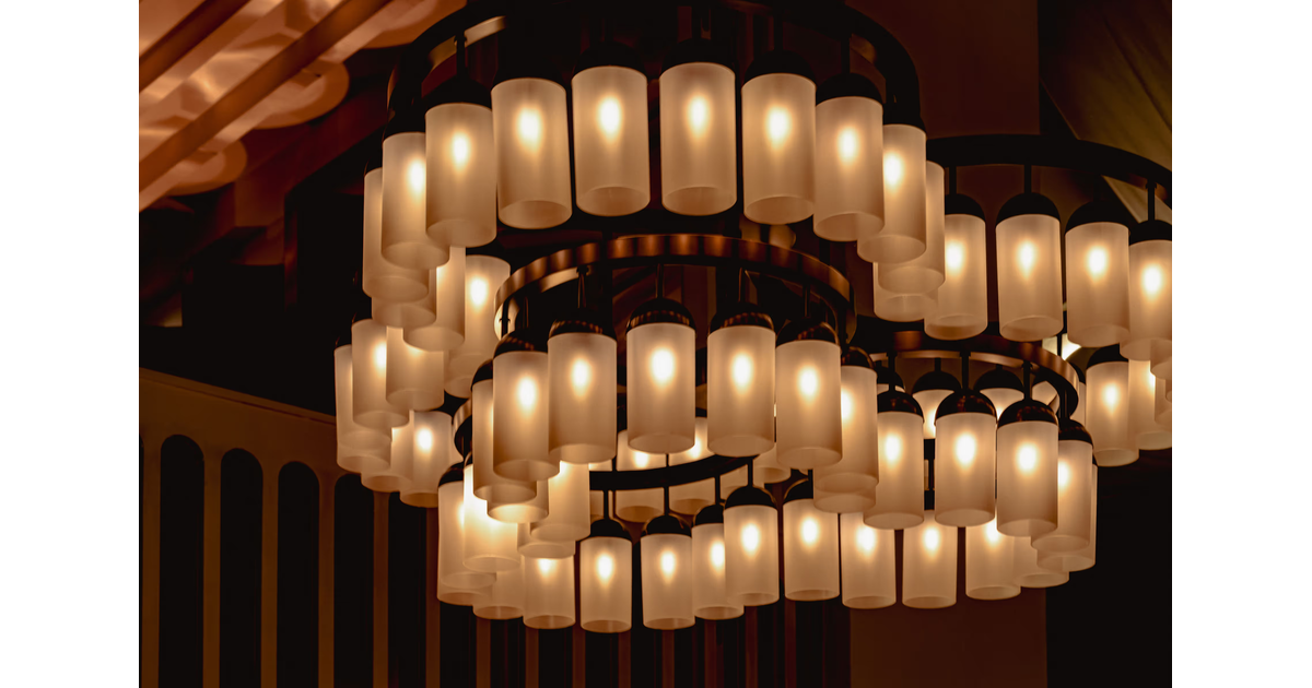 Modern circular chandelier with multiple warm-lit cylindrical lamps hanging from the ceiling.