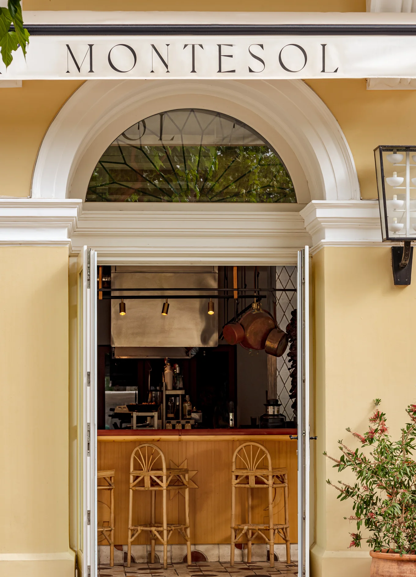 Open entrance to Montesol with bar stools and hanging copper pots inside.