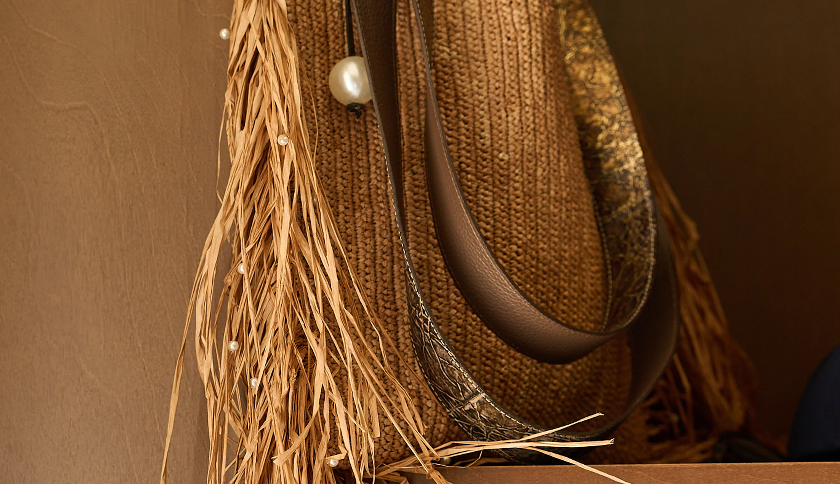 Stylish straw handbag with pearl embellishments displayed on a shelf in the boutique at Hôtel Régina Experimental, Biarritz.