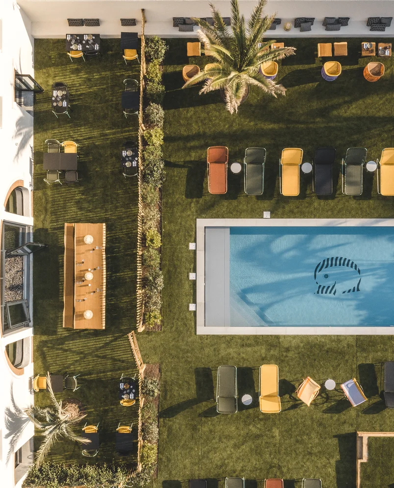 Veduta aerea della piscina e dei lettini dell'Hôtel Régina Experimental, Biarritz, circondato da un rigoglioso prato verde.
