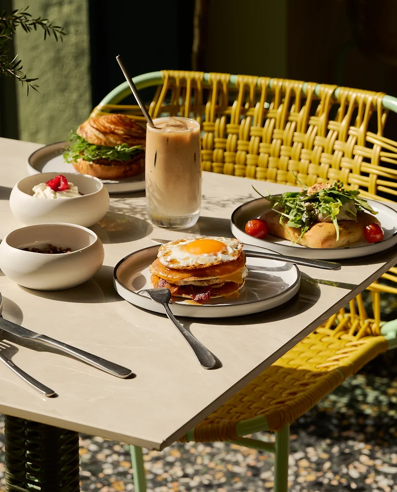 Gourmet breakfast served poolside at Hôtel Régina Experimental in Biarritz, featuring pancakes, iced coffee, and fresh pastries.