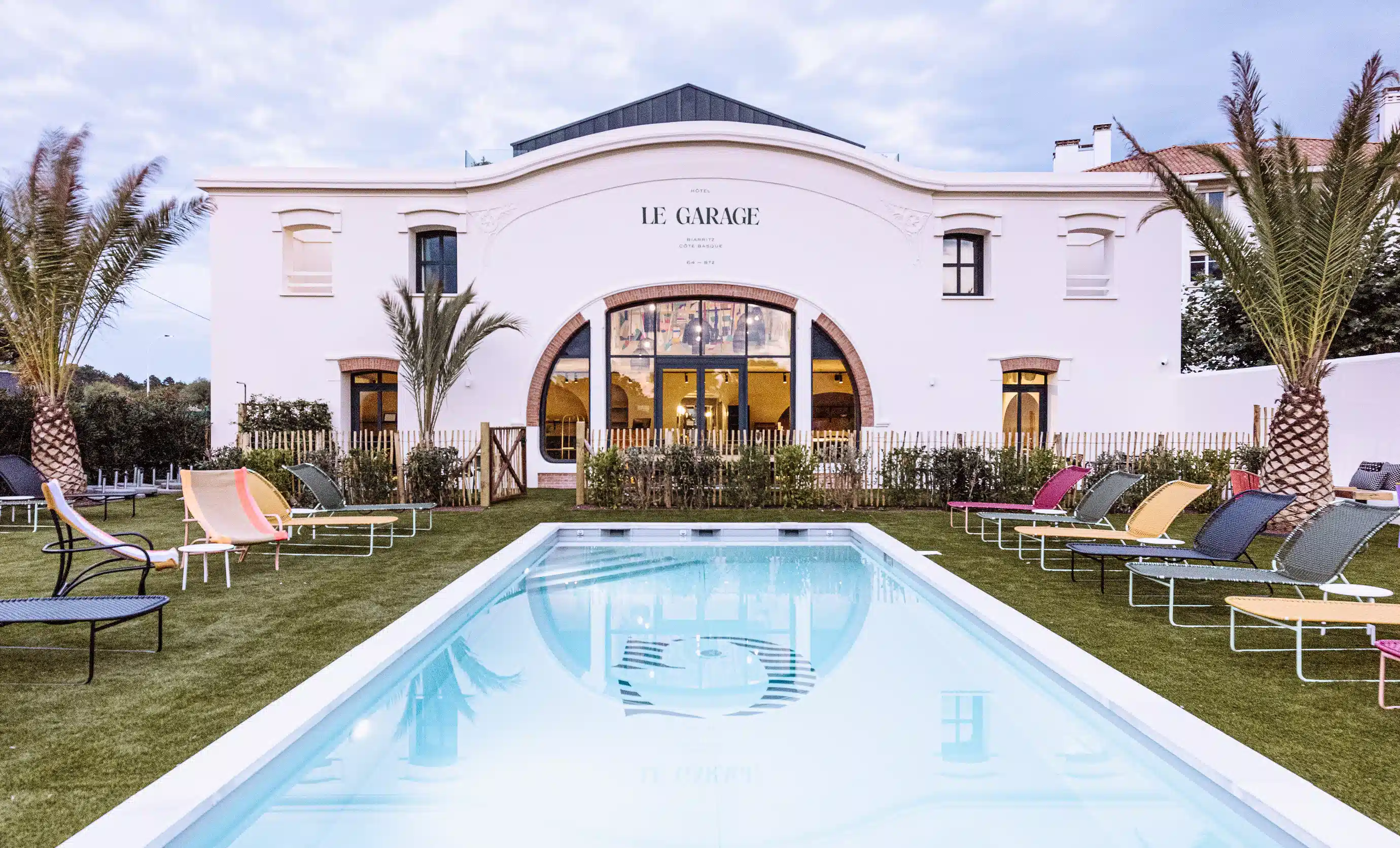 Exterior view of the white building and swimming pool of Hôtel Le Garage, Biarritz.